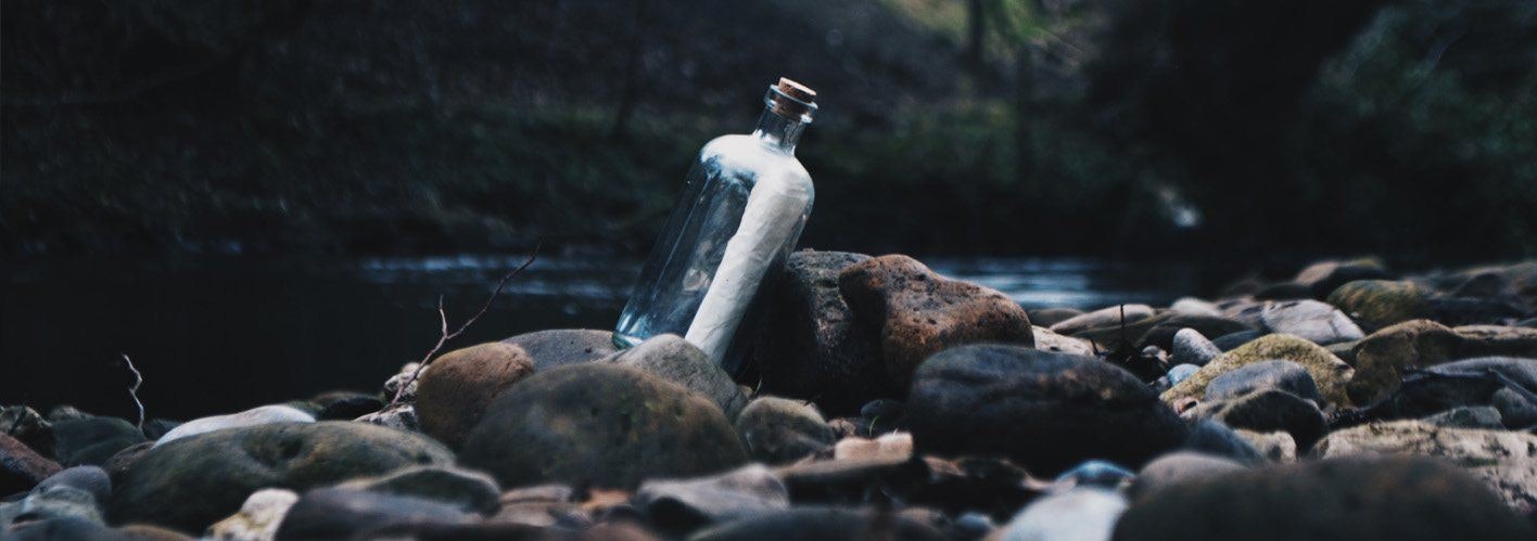 message in a bottle sitting on rocks